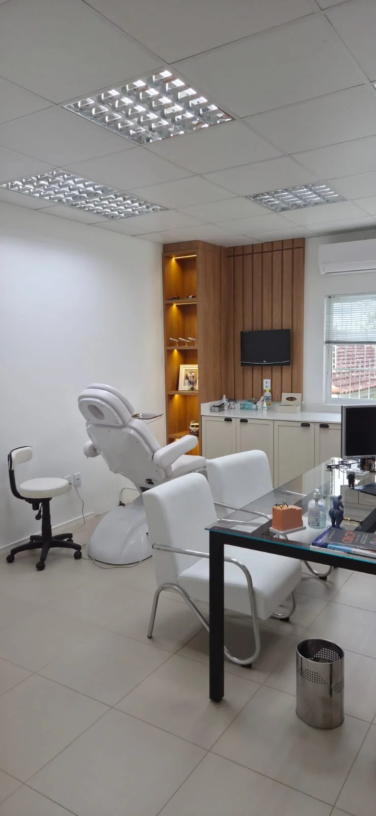 Ambiente de atendimento do doutor com cadeira de exame e acabamento em madeira
